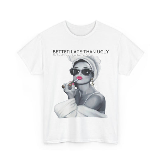 Elegant white graphic t-shirt showcasing a stylish figure applying lipstick, encapsulated by the slogan 'Better Late Than Ugly,' promoting a blend of humour and sophistication in fashion.