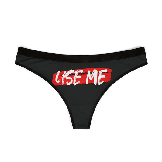 Stylish black thong lingerie displaying the playful phrase 'USE ME' in vibrant red, perfect for adding whimsy to an intimate wardrobe.