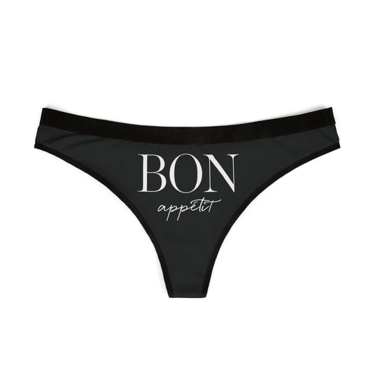 Stylish black thong showcasing the cheeky saying 'BON appétit' in an upscale font, perfect for adding a touch of whimsy to lingerie collections.