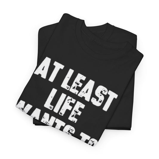 Stacked black unisex cotton t-shirts displaying the humorous slogan 'AT LEAST LIFE WANTS TO FUCK ME', perfect for making a bold statement in everyday fashion.