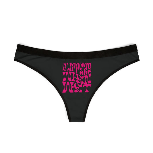 Elegant black thong showcasing the playful 'SLIPPERY WHEN WET' graphic in bold neon pink, a perfect combination of comfort and allure for the modern woman.