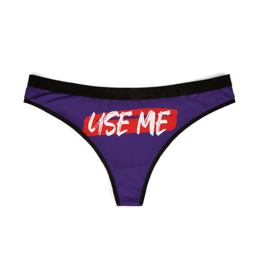 Chic front view of a luxurious purple thong with a striking black waistband, showcasing playful 'USE ME' text in white against a seductive mauve hue.