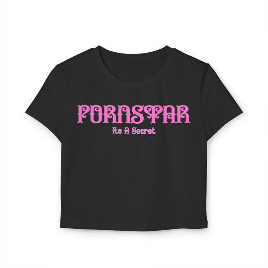 Elegant black cropped t-shirt showcasing the cheeky phrase 'Pornstar It's A Secret' in a bold pink stylized font, crafted from soft organic cotton for a luxurious feel.