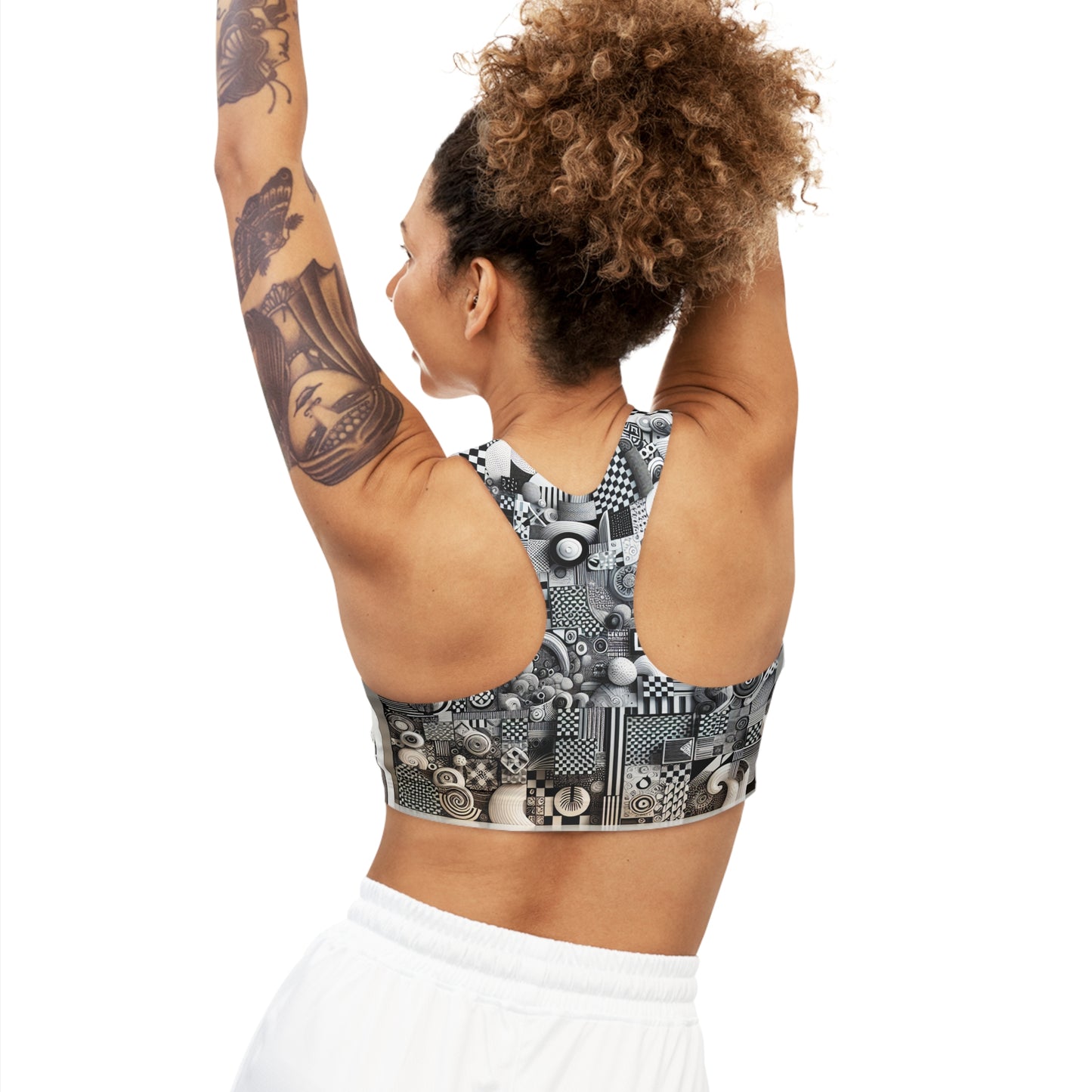 Chic Sports Bra from Valentina Belleveau featuring modern patterns, showcased on a model with curly hair and tattoos, raising her arms for an active pose. Perfect for ultimate comfort and support during any fitness routine.