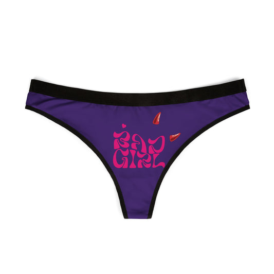 Elegant view of hot pink 'Bad Girl' thong panties with cheeky cut and playful devil motifs against a luxurious purple backdrop.