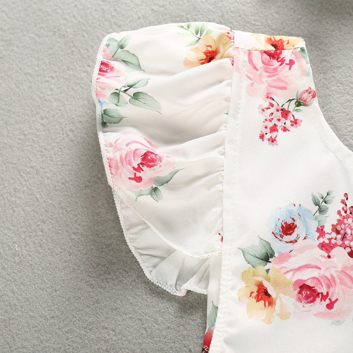 Side view detail of the Luxurious 100% Cotton Floral Romper for Baby Girls, highlighting the elegant floral patterns and ruffled sleeve design.
