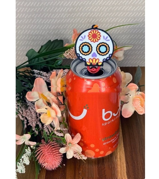 Elegant Skull Design Soda Can Tab Opener with Keychain Strap, perfectly positioned on an orange soda can surrounded by delicate flowers, blending style with practicality.