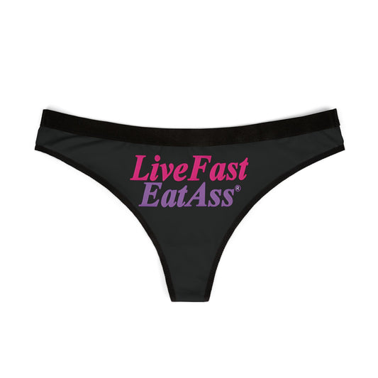 Elegant black thong panties showcasing the eye-catching phrase 'Live Fast Eat Ass' in striking pink and purple, perfect for adding a daring touch to any lingerie collection.