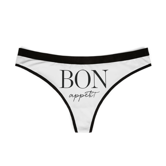 Stylish thong displaying 'BON appétit' in sophisticated font, adorned with refined black borders, ideal for playful yet luxurious lingerie collections.