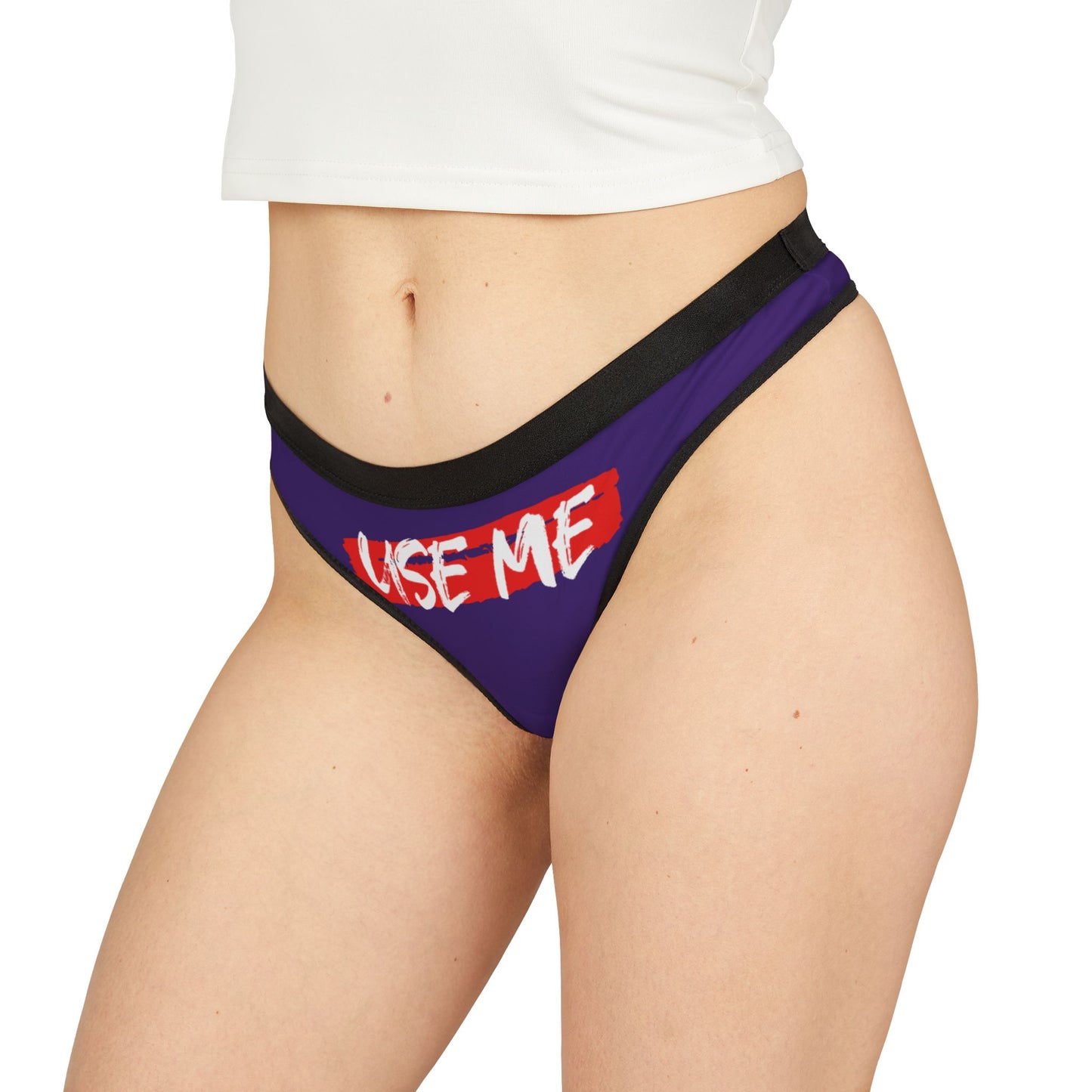 Sophisticated side perspective of a purple thong displaying cheeky 'USE ME' inscription in bold white, perfect for a whimsical and playful lingerie collection.