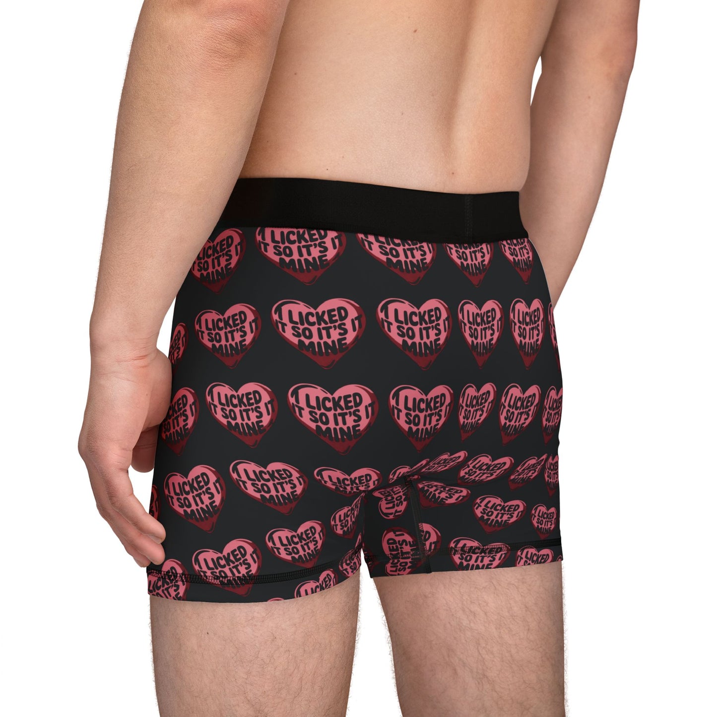 Side view of a model in Valentine's Naughty Cheeky Men's Boxer Briefs, featuring a humorous heart graphic declaring 'I LICKED IT SO IT'S MINE'.