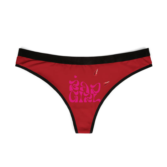Luxurious red thong panties featuring a bold 'Bad Girl' design in vibrant pink with devil horns, set against a pristine white background.