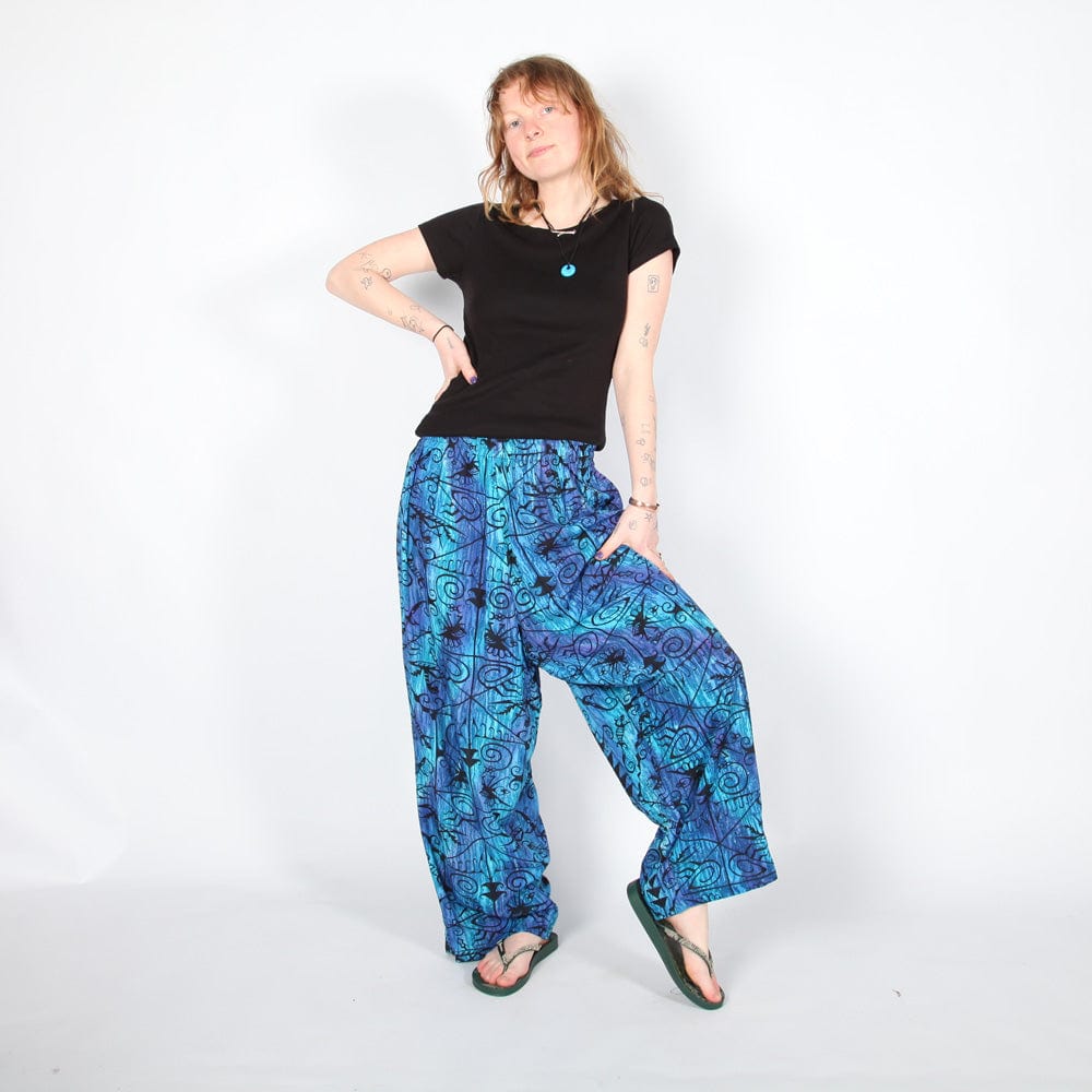 Model wearing flowy lizard print trousers styled with a plain top, embodying bohemian chic, perfect for summer outings or festivals.
