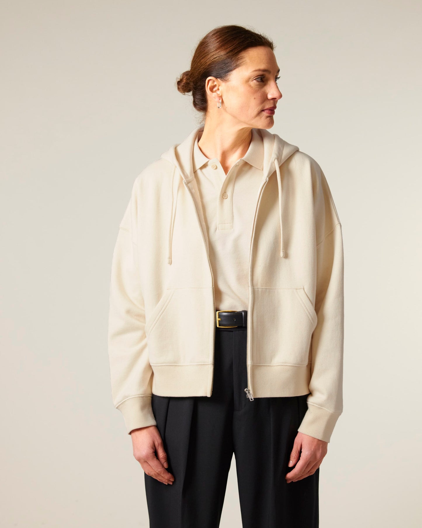 Full-length image of a woman in a medium fit organic cotton hoodie, demonstrating its flattering adjusted length and set-in sleeve design.