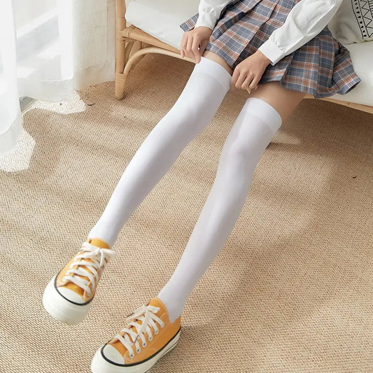 Women's Black White Solid Color Long Socks Stockings displayed on a model wearing a plaid skirt and yellow sneakers, showcasing the sleek white design.