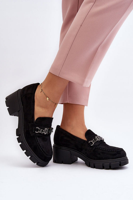 Sophisticated black eco-suede women's moccasins from Step in Style, adorned with a decorative chain and set on a stylish 5cm heel, paired with contemporary pink trousers.