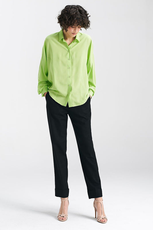 Chic lime oversize long sleeve shirt by Nife, paired with black trousers and strappy heels, emphasizing its versatility for stylish summer outfits.