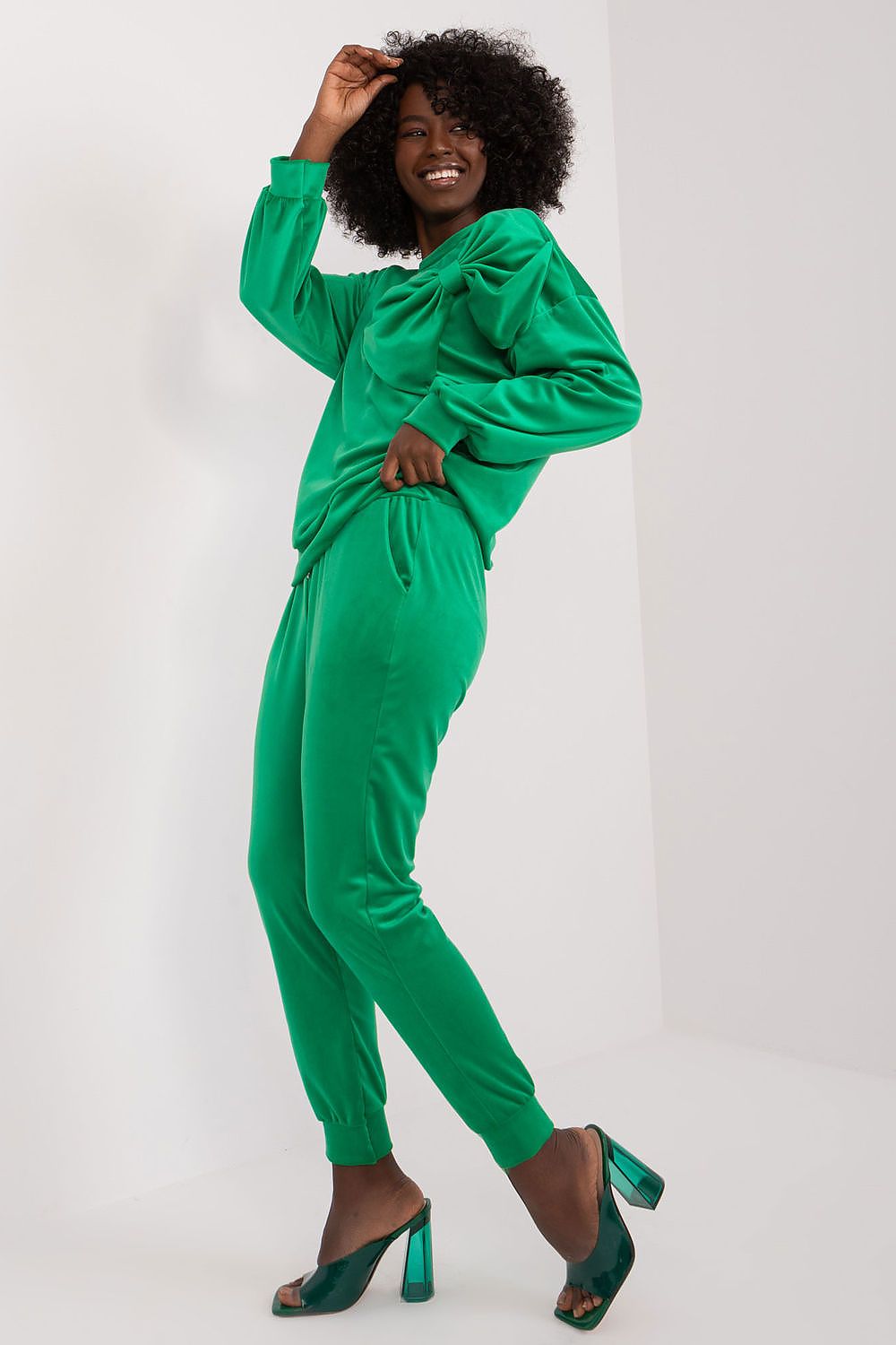 Elegant woman wearing a green velour tracksuit by Italy Moda, highlighting the unique bow detail and sporty design, perfect for a fashionable yet comfortable look.