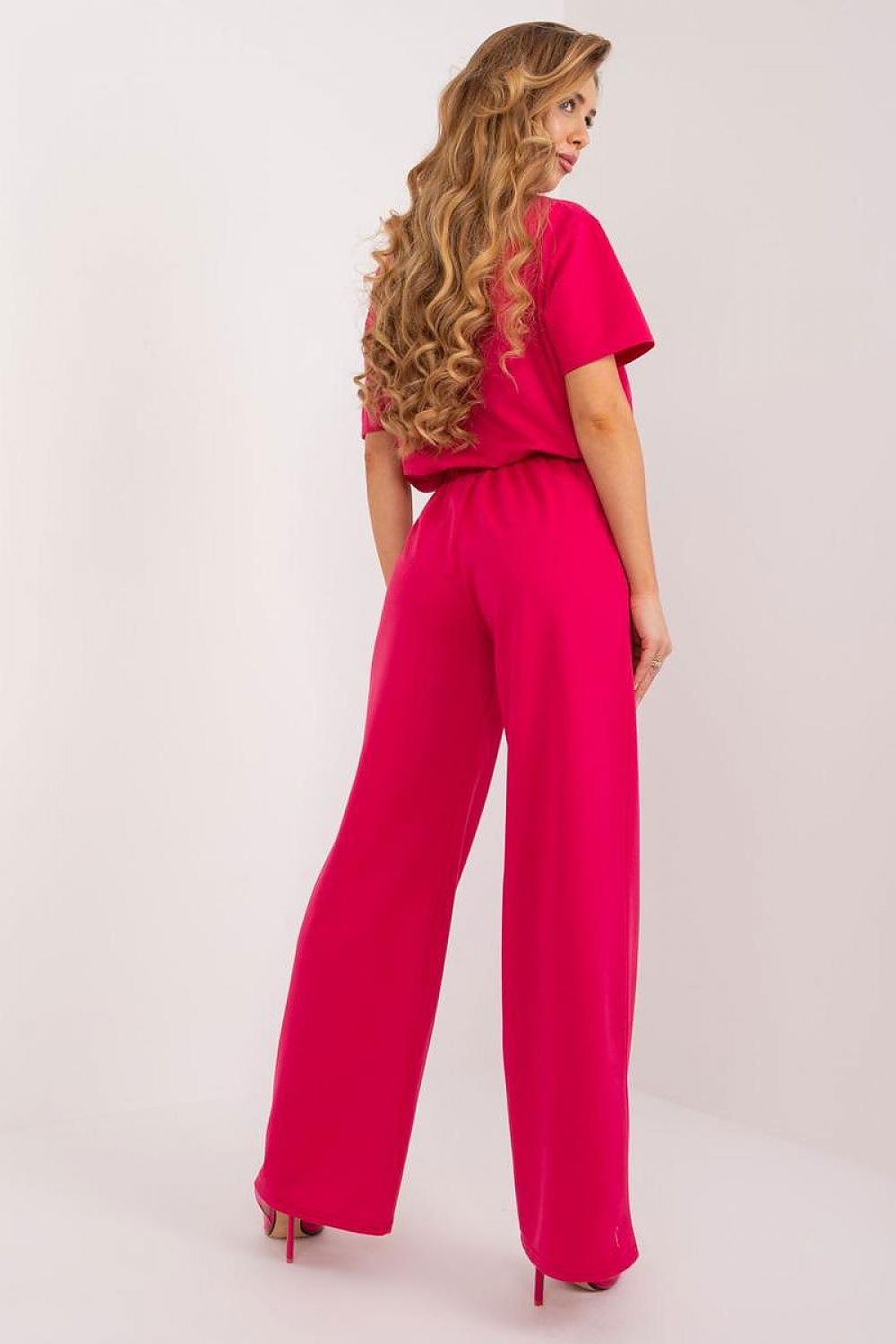 Stylish back view of a model in Lakerta high rise cotton blend trousers in striking pink, highlighting the flattering silhouette and luxurious design.