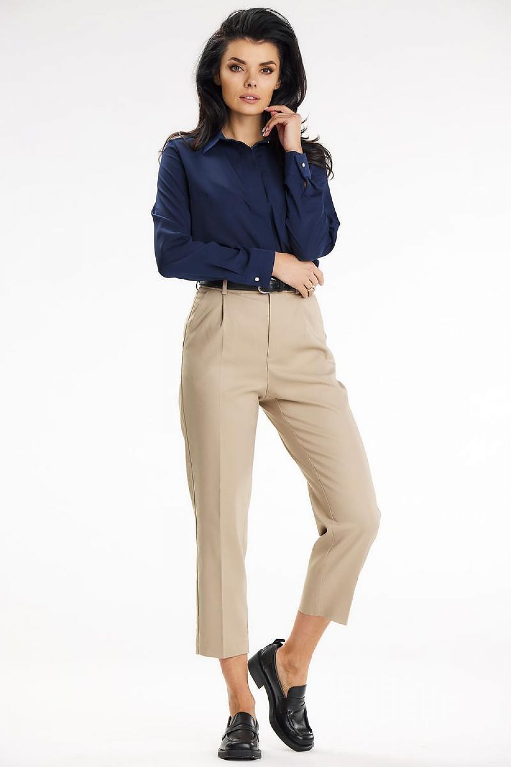 Standing pose in a sophisticated navy Awama long sleeve shirt, highlighting its versatility with classic beige trousers.