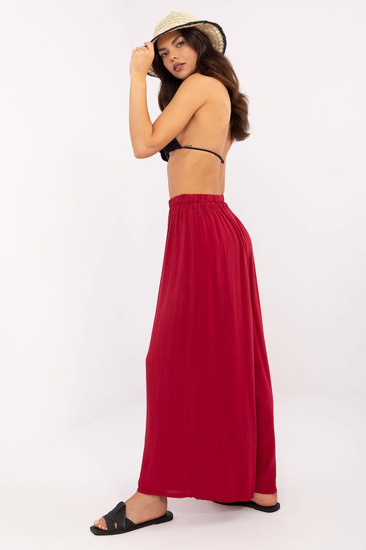 Profile view of a model wearing red high-waisted wide-leg viscose trousers by Och Bella. The lightweight fabric offers elegance and comfort, ideal for warm weather attire.