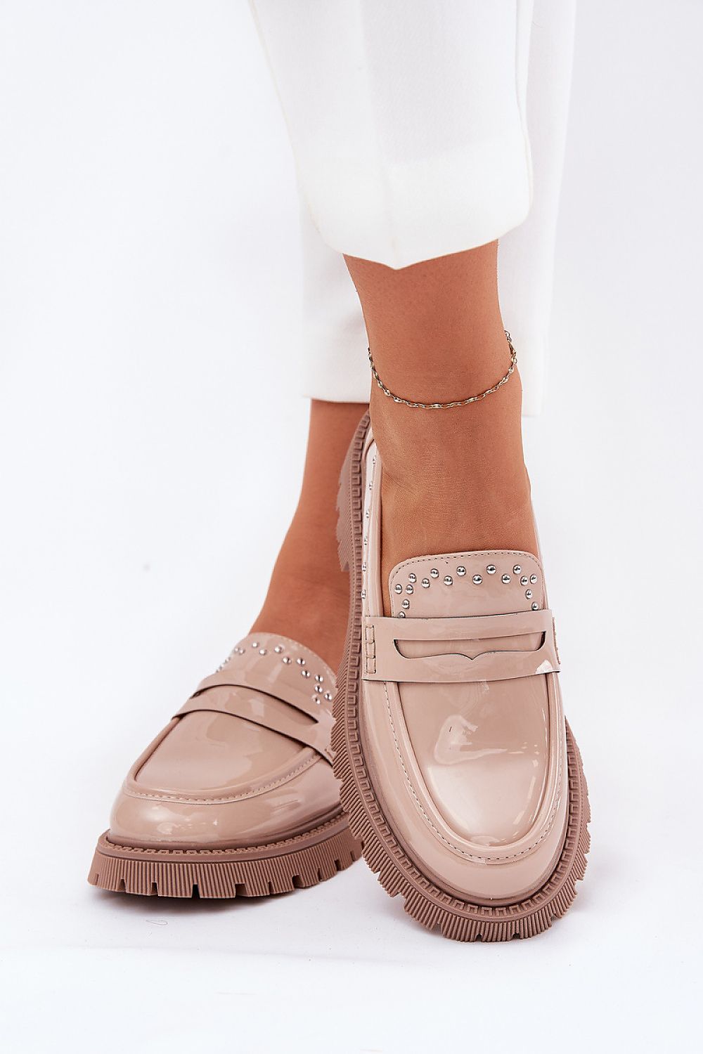 Chic women's moccasins in patent eco leather by Step in style, featuring delicate embellishments and partnered with tailored trousers for a sophisticated look.