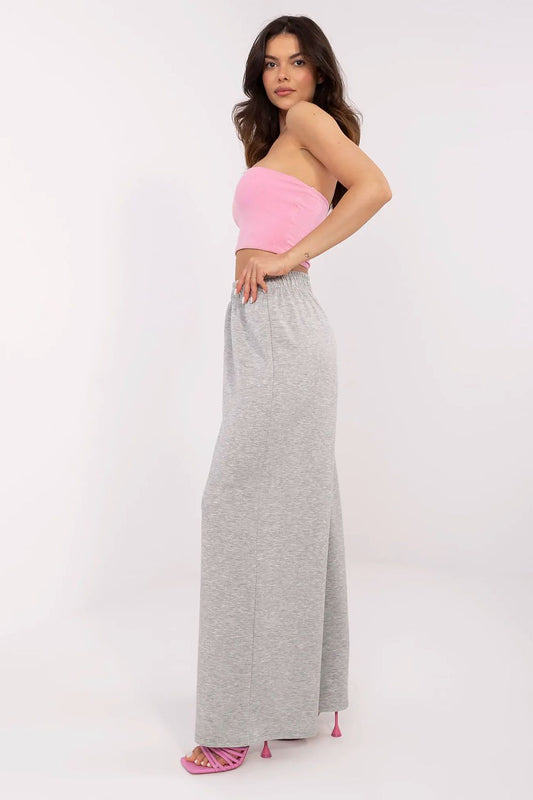 Side view of a fashionable woman in a pink strapless top with high-waist grey wide leg trousers, embodying Italy Moda's modern and comfortable aesthetic.