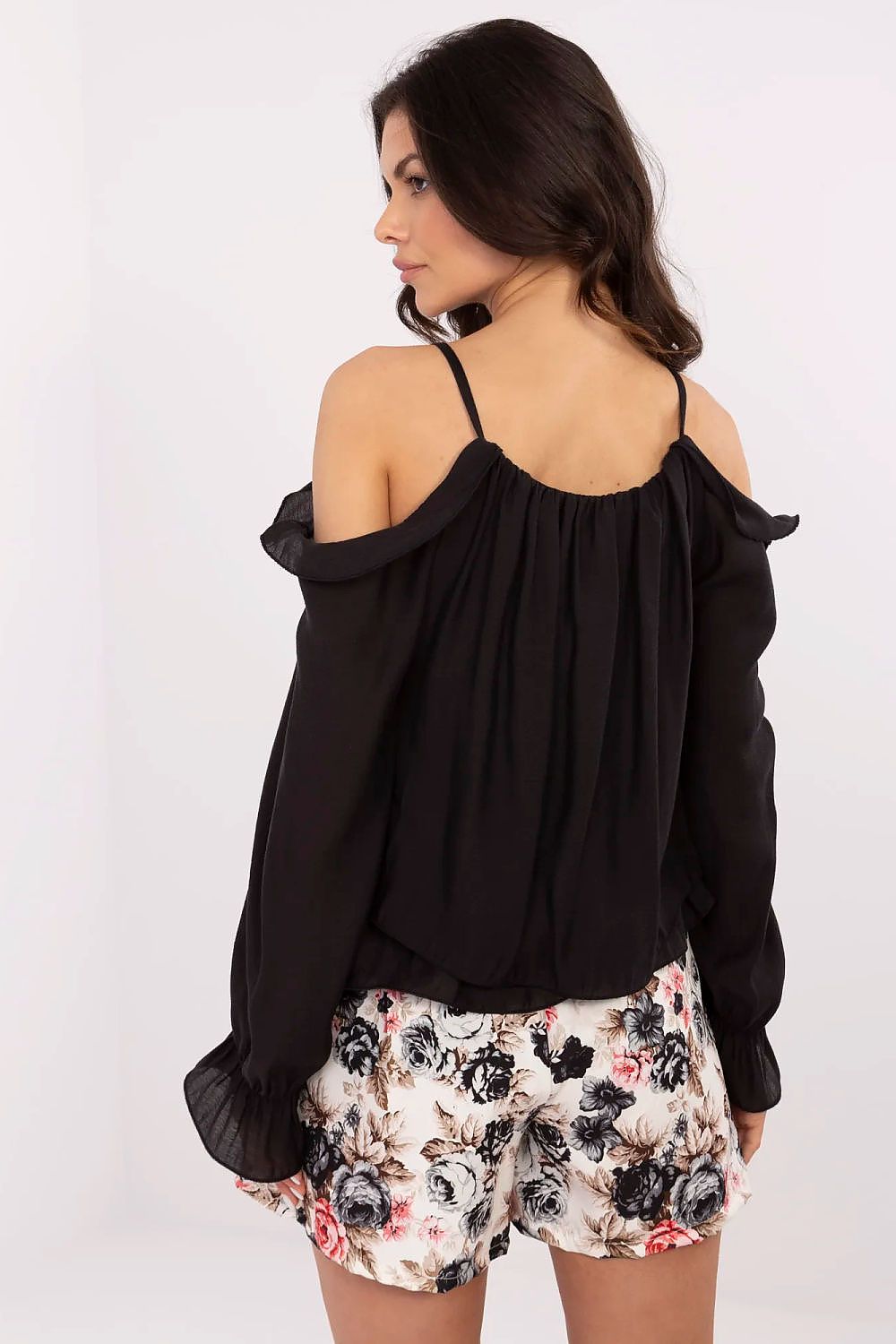 Model wearing an Italy Moda off-the-shoulder blouse styled with elegant pants, highlighting the blouse's versatility and refined design.