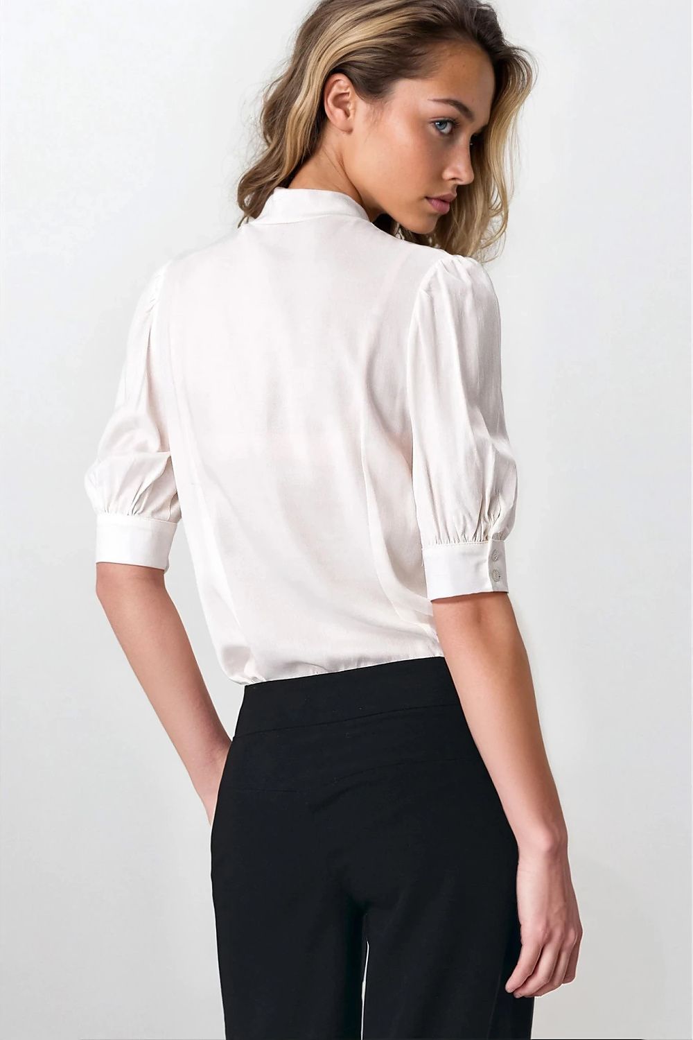 Chic Nife blouse in a luxurious setting, designed with a neck tie and graceful puffy sleeves, ideal for those seeking a blend of elegance and comfort.
