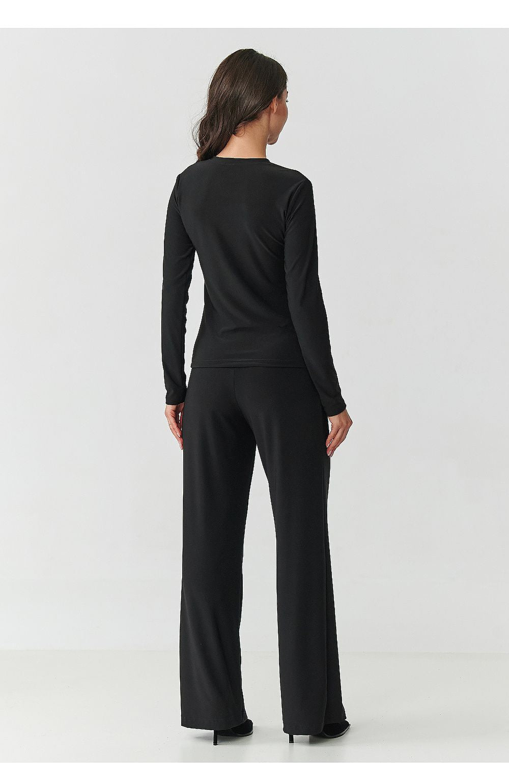 Close-up of elegant black blouse with transparent inserts and high-waisted wide-legged trousers from the Makadamia women's set, showcasing timeless fashion.