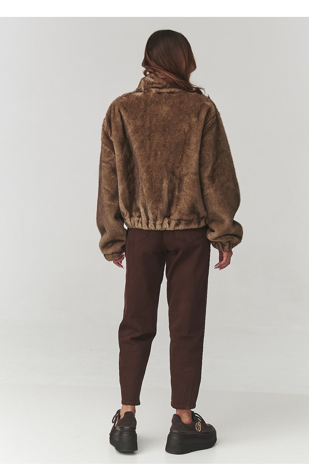Stylish woman wearing Makadamia Women's Eco Fur Jacket in warm mocha, demonstrating versatility for both casual and formal occasions during the cold seasons.