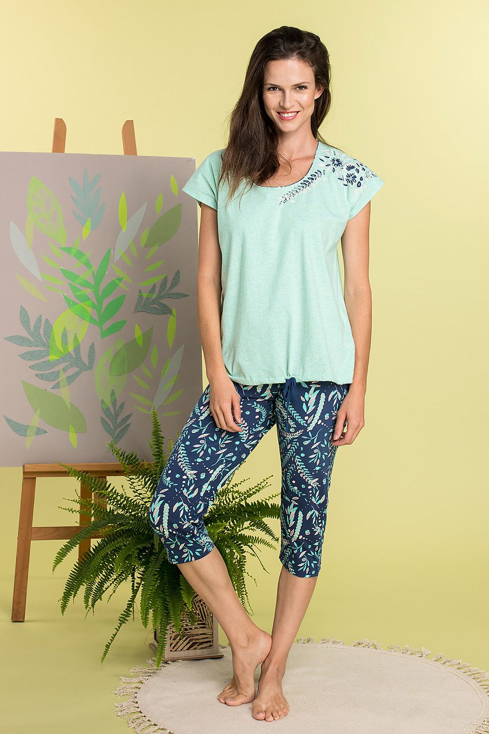 Elegant ladies cotton pyjamas set by Key featuring a short-sleeved floral print top and patterned ribbed trousers, set against a soft pastel backdrop.