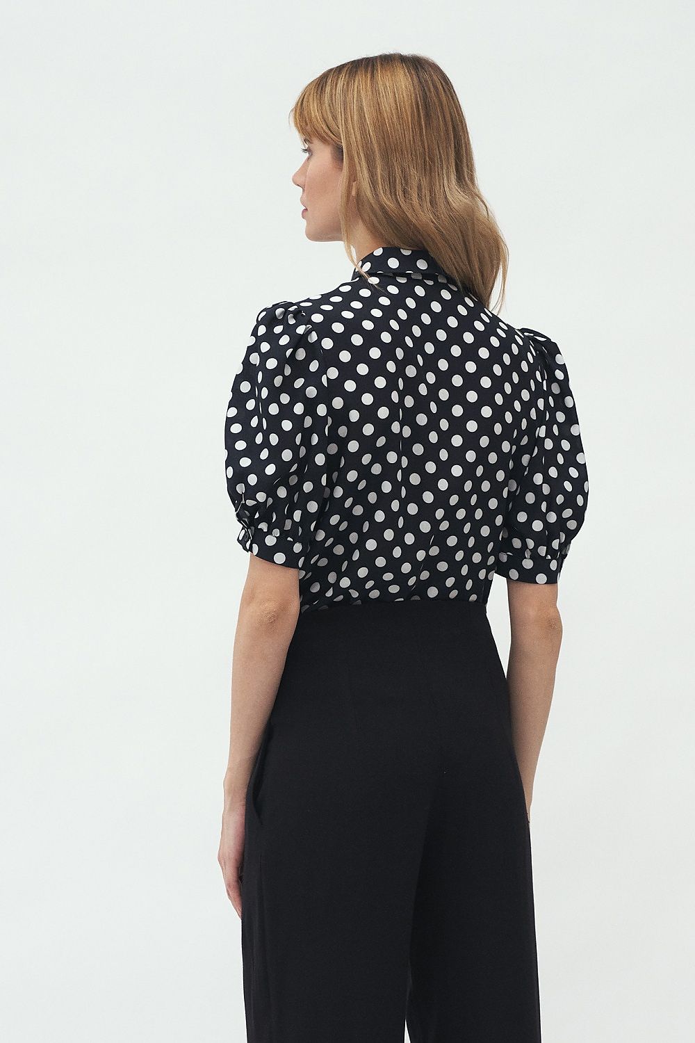 Back view of the luxurious short sleeve shirt by Nife in a chic polka dot design, paired with tailored black trousers, ideal for refined summer fashion.