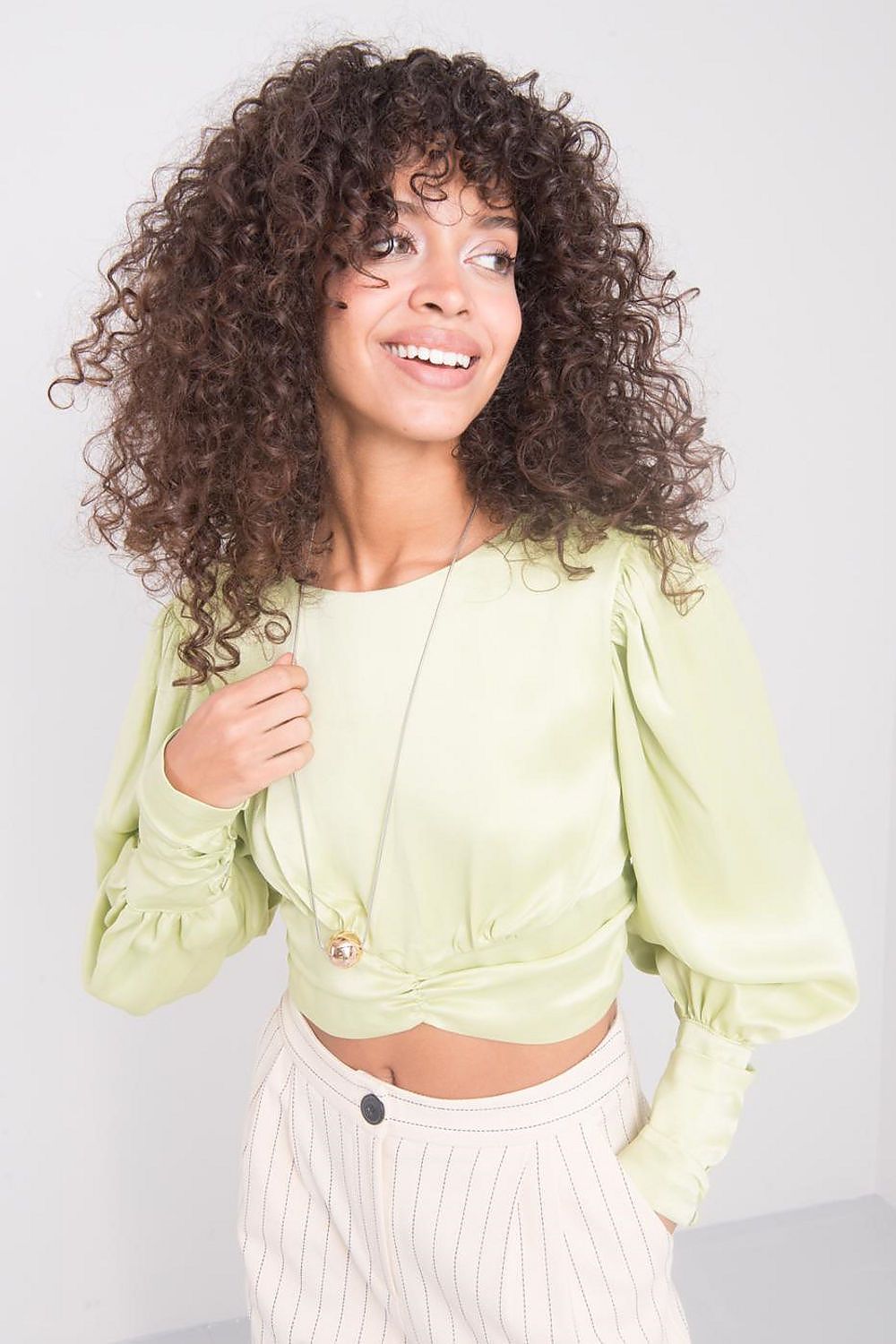 Charming model wearing a lime long sleeve viscose blouse with distinctive back detail by Sally Fashion, effortlessly accentuating her style alongside tailored striped trousers for a luxury look.