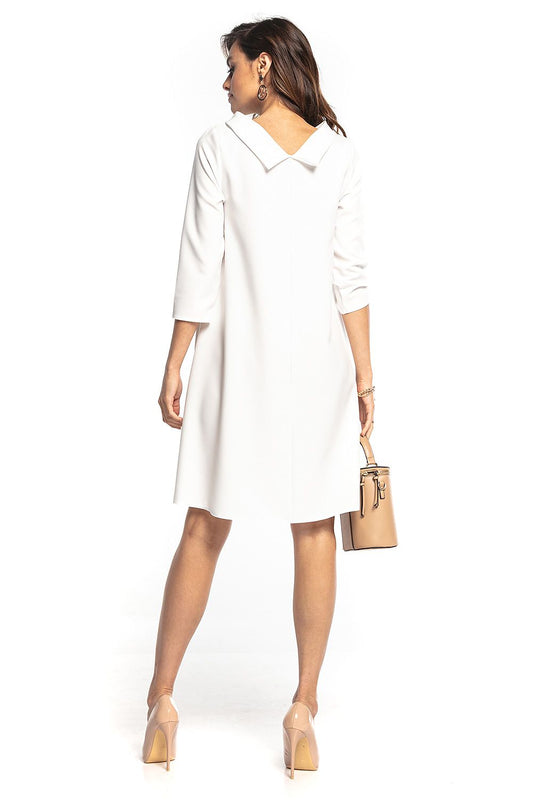 Back view of the elegant Jackie Kennedy style midi dress by Tessita, featuring a folded collar and 3/4 sleeves, showcased in a pristine white colour. The model elegantly displays the flowy trapeze fit.