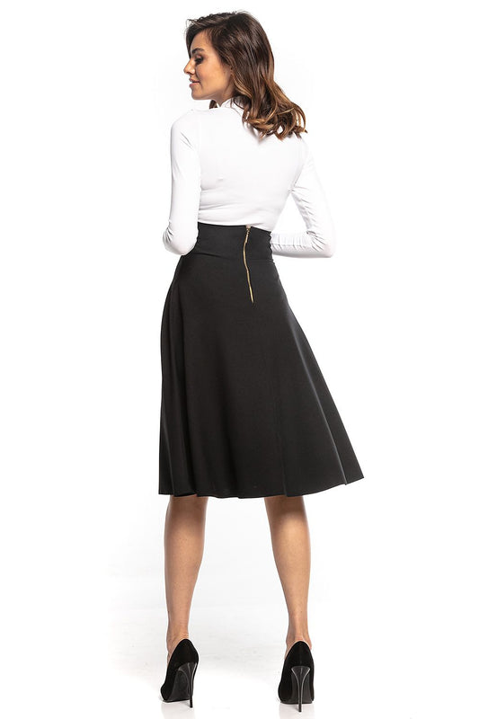 Back view of Tessita high-waisted black midi skirt with decorative zipper, paired with a chic white long-sleeve top, epitomising timeless elegance.
