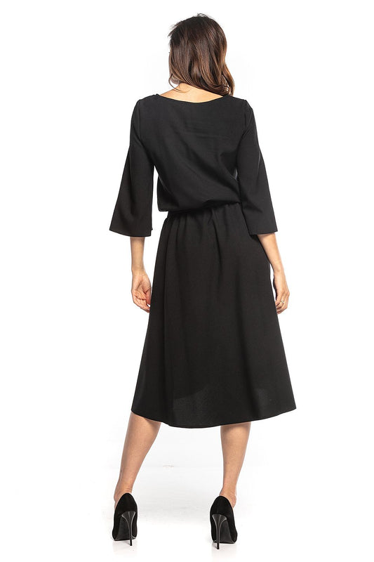Rear view of the sophisticated asymmetrical midi dress with 3/4 sleeves by Tessita, highlighting the elegant flowing fabric and flattering fit.