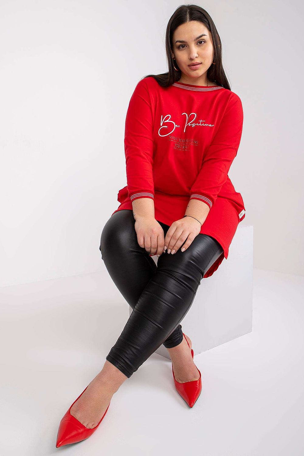 Chic red tunic featuring 3/4 sleeves and stylish slip pockets, paired elegantly with black leather leggings and striking red heels, embodying modern luxury.