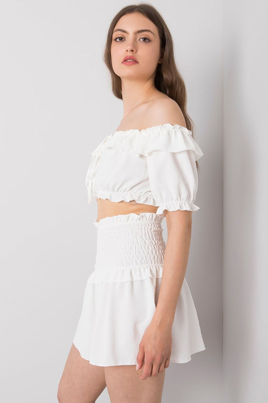 Side view of a model in the Och Bella Women's Short Summer Skirt with Wide Elastic Waistband paired with a chic white off-the-shoulder top, ideal for stylish summer outings.