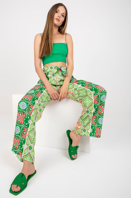 Italy Moda Women's High-Waisted Wide-Leg Trousers with Elastic Waistband - Elegant Comfort Pants showcased in a stylish seated pose, featuring bold floral patterns and a luxurious green hue, perfect for sophisticated leisure wear.