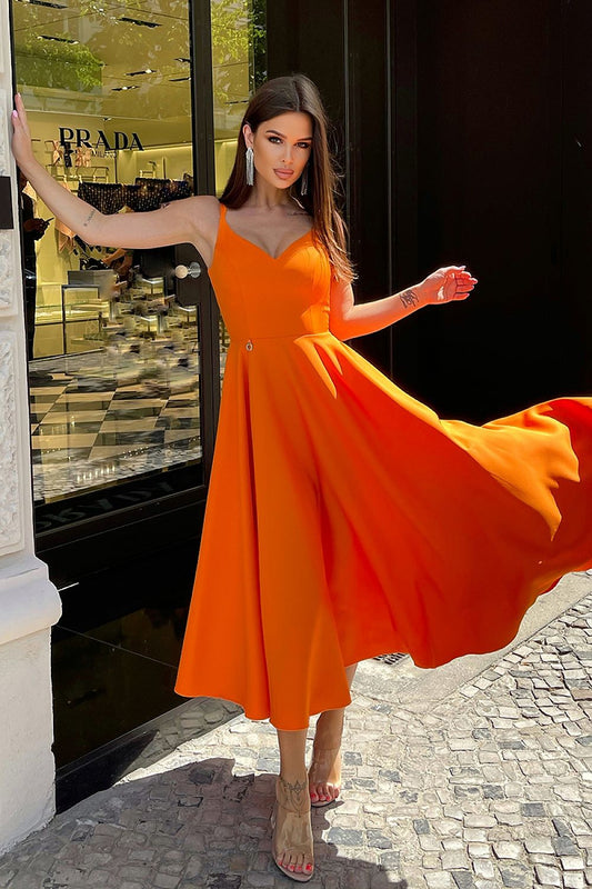 Elegant Bicotone Midi Dress with Shoulder Straps, Flared Skirt and Exposed Back - Model gracefully twirling in the stunning orange midi dress, capturing the essence of femininity and elegance against a designer storefront.