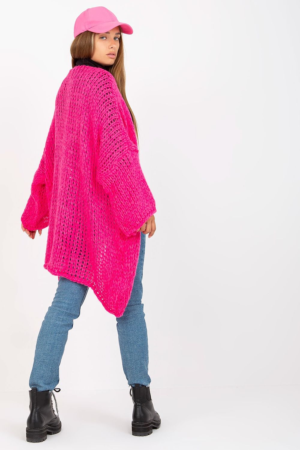 Luxury Women's Long Sleeve Cardigan by Och Bella displayed by model from the back, illustrating the bold pink hue and intricate knit texture, stylishly combined with denim and a pink cap.
