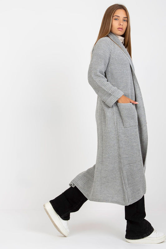 Side view of the Elegant Long Unbuttoned Cardigan by Och Bella, highlighting its soft texture and sophisticated design, layered over a turtleneck top and elegant black pants.