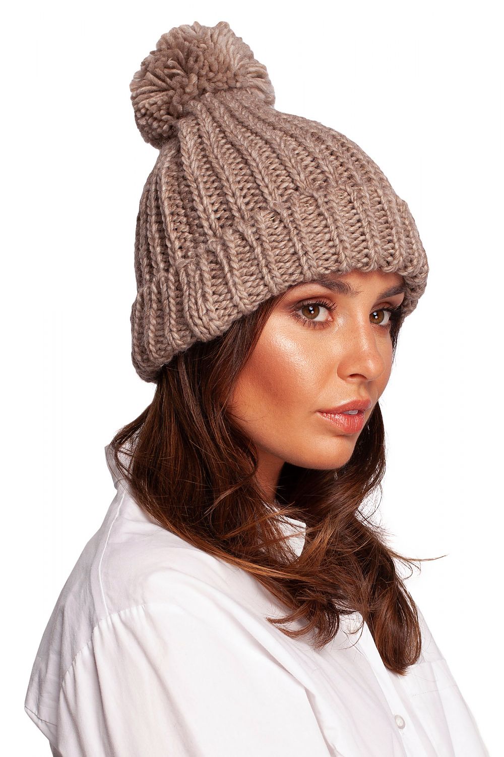 Elegant woman showcasing a luxurious pom-pom beanie hat, made from a premium blend of 75% acrylic, 15% nylon, and 10% wool, perfect for winter warmth and style.