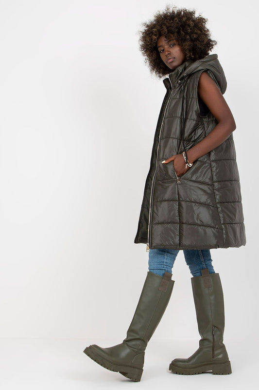 Elegant model showcasing an olive green quilted down vest with a detachable hood, styled with stylish tall boots and blue jeans, perfect for luxury casual wear.