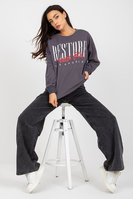 Fashion-forward model showcasing a chic long-sleeved cotton sweatshirt with striking graphic design, paired with stylish wide-leg jeans for a contemporary look.