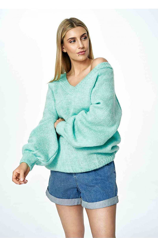 Chic fashion model showcasing a mint green deep V-neck sweater by Figl, featuring prominent wide sleeves, complemented by rolled-up denim shorts for a relaxed yet fashionable look.