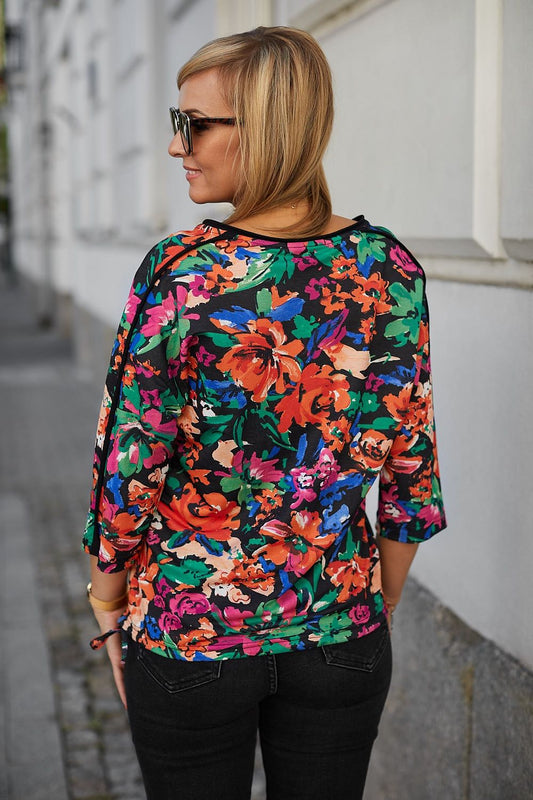 Elegant floral kimono style blouse by La Aurora, showcasing vibrant colours against a black backdrop, highlighting falling sleeves and soft knitted cotton fabric. Ideal for a chic, luxurious outfit.