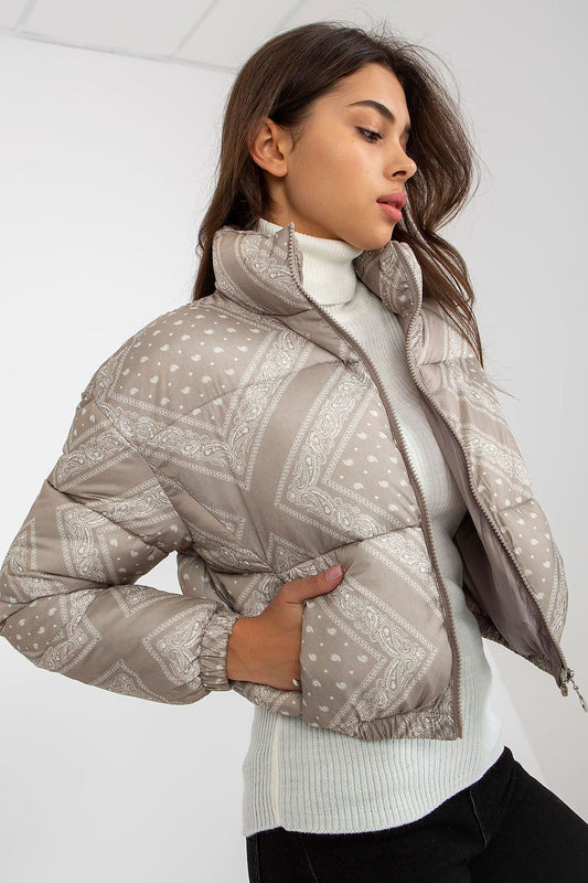 Stylish woman's NM polyester cropped jacket showcasing unique patterns in soft beige, complemented by a form-fitting white turtleneck. Ideal for sophisticated casual wear.