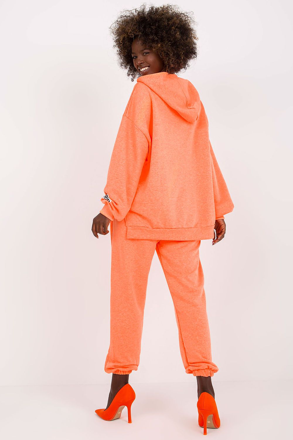 Stylish women’s luxe cotton-blend sweatshirt and pants set in vibrant coral. Featuring a relaxed hooded sweatshirt and tapered pants, the set embodies comfort with elegance. Perfectly paired with striking orange heels for a chic, sophisticated look.